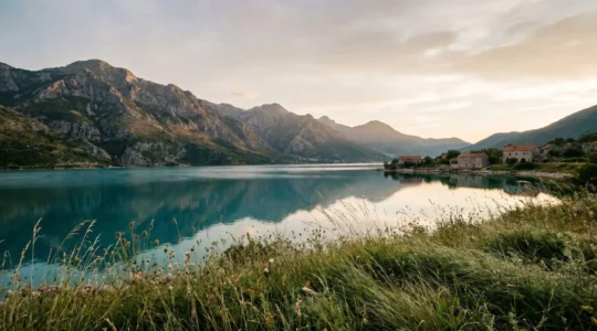 Dramatic wide panoramic view of Balkan mountain landscape with pristine lake waters and ancient architecture along the shore at golden hour