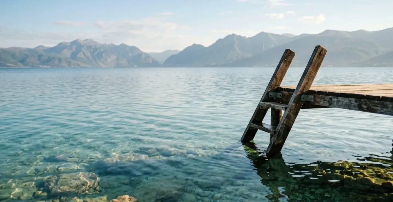 Pristine turquoise waters of Lake Ohrid with mountain backdrop and sun reflection creating natural clarity