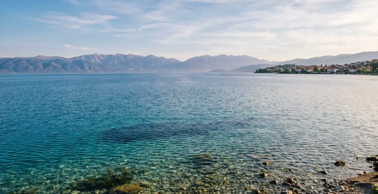 Pristine ancient Lake Ohrid surrounded by mountains with crystal-clear turquoise waters reflecting sunlight under a vast blue sky