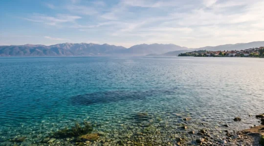 Pristine ancient Lake Ohrid surrounded by mountains with crystal-clear turquoise waters reflecting sunlight under a vast blue sky