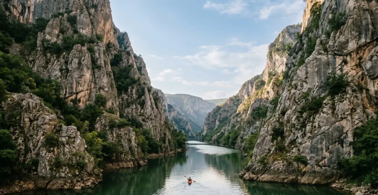 Dramatic limestone cliffs towering over emerald Treska River waters in Matka Canyon with kayaker exploring peaceful natural gorge near Skopje
